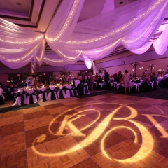 Monogram rotating on dance floor with colored LED uplighting