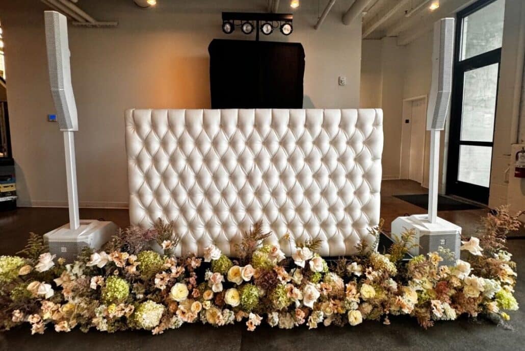 White tufted booth with white speakers and floral arrangement scaled e1756948984394